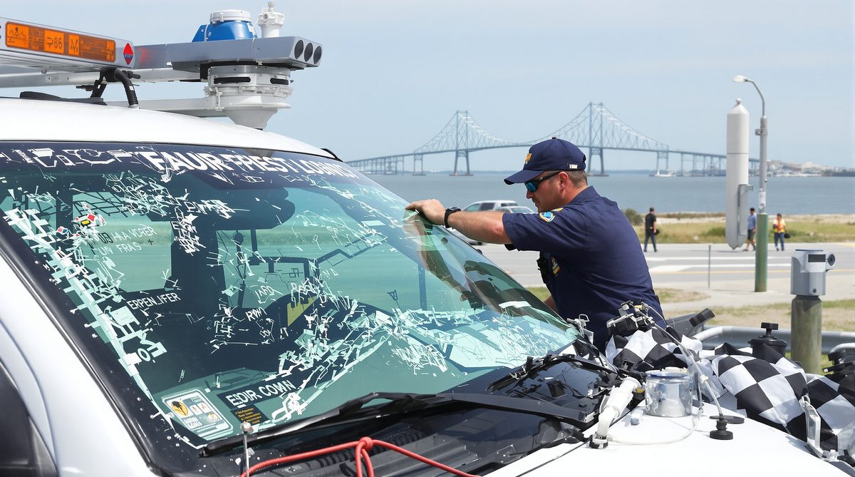 Auto glass technician replacing shattered windshield on vehicle with Corpus Christi Texas Harbor Bridge visible in background