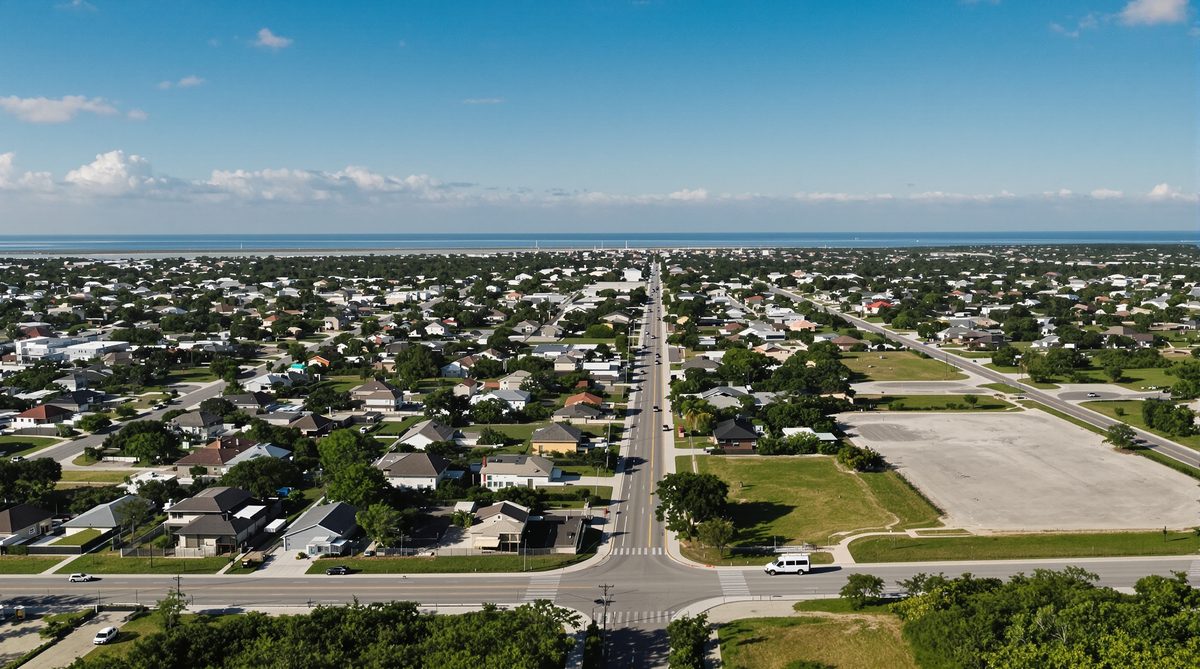 Aerial drone view of South Texas coastal neighborhood with bay visible on horizon — CC Auto Glass Pros mobile service area Corpus Christi TX