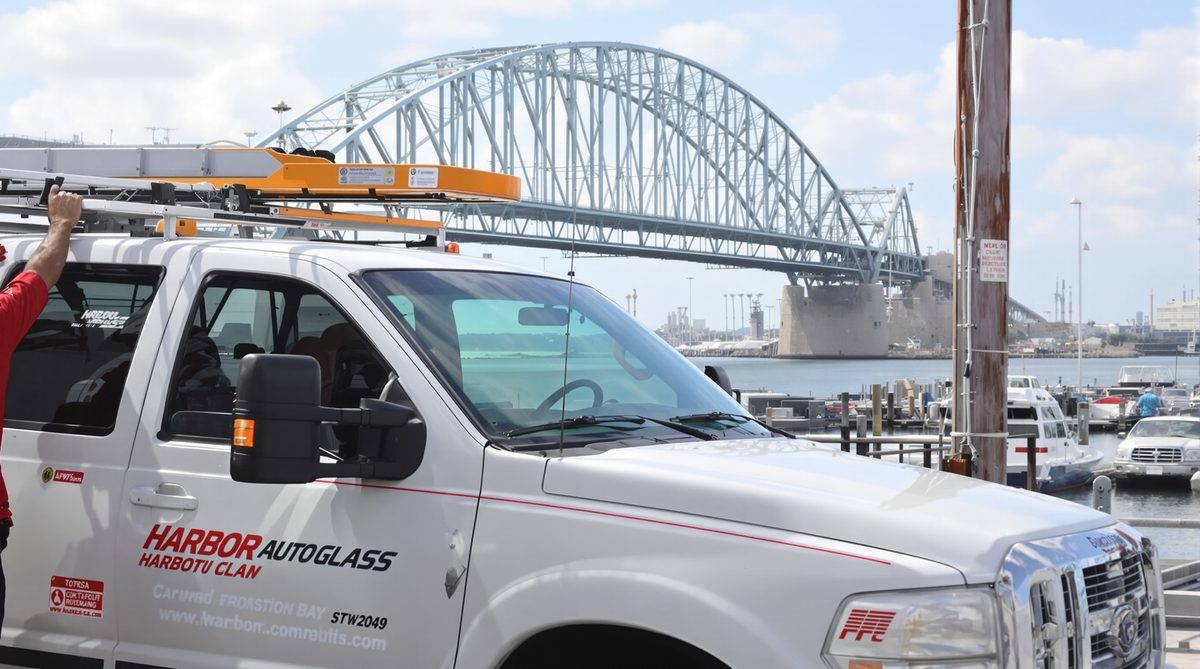 Auto glass service truck with glass rack near Portland Texas waterfront with Harbor Bridge arch visible over Corpus Christi Bay in background